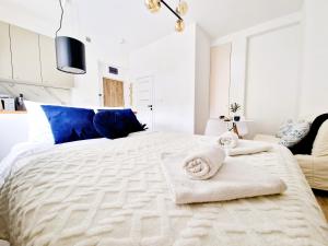华沙J&W Apartments Grójecka Glam Flat的白色卧室配有一张大床和毛巾