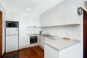 埃利奥特港Dolphins Beachfront Apartment No 4的厨房配有白色橱柜和白色冰箱。