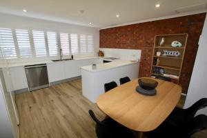 埃利奥特港Southern Sands' Beachfront Apartment的厨房配有木桌和砖墙