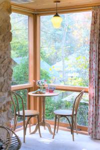 克拉佛斯Adelaide Hills Camellia Cottage Wifi的窗户客房内的桌椅