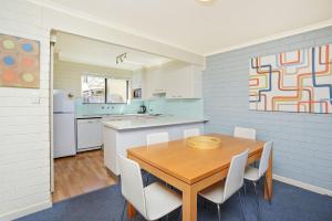 埃利奥特港南海海滨公寓 的厨房以及带木桌和椅子的用餐室。