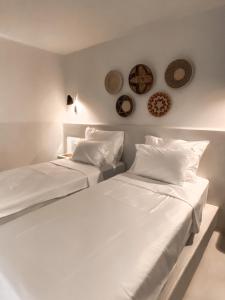 图兰克Pilos Suites的墙上有盘子的房间,配有两张白色的床