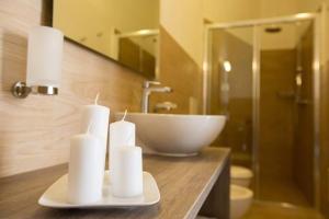 托雷圣乔万尼乌La Giara Resort的浴室设有水槽,柜台上设有三根蜡烛