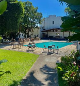 瓦索拉斯Mara Palace Hotel的庭院内一个带桌椅的游泳池