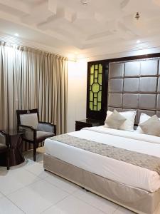 吉赞Aldar Hotel的一间卧室配有一张大床和一把椅子