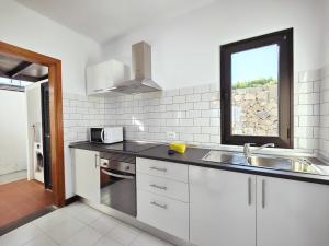 蒂亚斯Casa María的厨房配有白色橱柜、水槽和窗户。