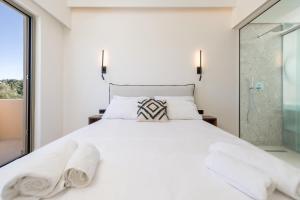 达西亚Little Corfu的卧室配有白色的床和玻璃淋浴间