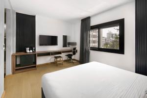 尼科西亚Urban Habitat Executive Suites的一间卧室配有一张床、一张书桌和一台电视
