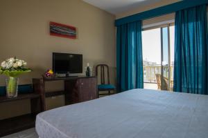 圣伊西德罗Hotel Aeropuerto Sur的一间卧室配有一张床、一台电视和一个阳台