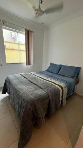 里约达欧特拉斯Pousada Pé na Areia Rio das Ostras的一间卧室配有一张带蓝色枕头的床和一扇窗户。