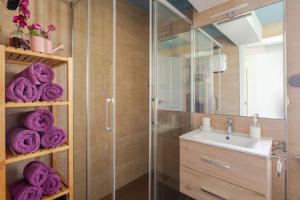 圣地亚哥－德孔波斯特拉VutSanClemente Exclusivo a 100 metros de la Catedral的一间带玻璃淋浴和紫色毛巾的浴室