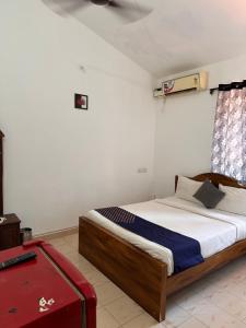 Goasun and sea guest house calangute的一间卧室配有一张床和一个红色的行李箱