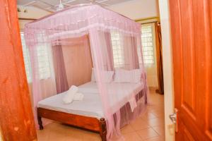 乌昆达Karura and friends airbnb (affordable)的一间卧室配有一张带粉红色窗帘的天蓬床