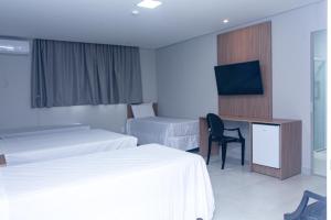 圣保罗Hotel Solar Paulista的酒店客房设有两张床、一张桌子和一台电视。