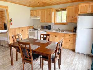 卡文迪西隐秘园地山林小屋的厨房配有木桌和白色冰箱。