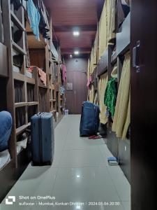 孟买ASRA DORMITORY For Male And Female的一间房间,有两只手提箱,坐在地板上