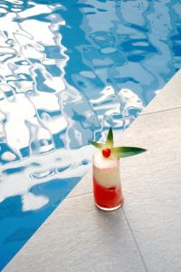 萨利纳斯Hotel Presidente Beach Salinas的坐在游泳池旁的桌子上喝一杯