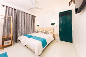 KendhooFasdheythere Inn Maldives的一间卧室设有两张床和一扇绿门