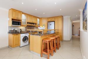 马盖特Lucien Sands 602的厨房配有木制橱柜和带凳子的台面