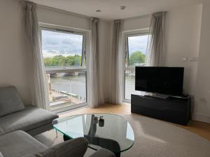 伦敦Entire Kingston Two bedroom Apartment Town centre & River view, 32 minutes to London Waterloo Station的带沙发和电视的客厅以及2扇窗户。