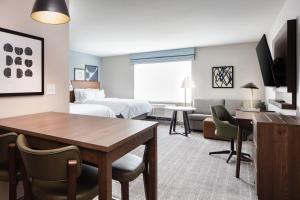 克拉尔维尔Staybridge Suites - Iowa City - Coralville, an IHG Hotel的酒店客房设有一张桌子和一间卧室。