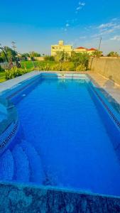拉合尔Luxury Farmhouse for Stay and Events的一座蓝色的大型游泳池,其建筑背景为: