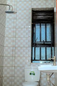 BulengaEQUATOR GATES HOTEL的一间带卫生间、水槽和窗户的浴室