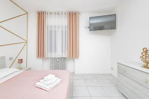 莱科Holidays的白色卧室设有粉红色的床和电视。
