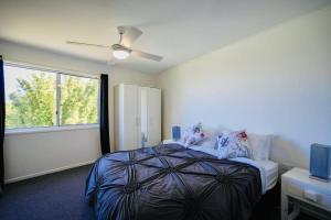 谭伯连山SERENE MOUNTAINVIEW RETREAT / TAMBORINE MOUNTAIN的一间卧室配有一张带吊扇和窗户的床。