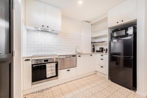 基督城Retro Retreat in Christchurch的厨房配有白色橱柜和不锈钢用具