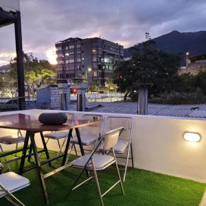 基多Casa Colon Quito Bed & Breakfast Hostel的草阳台的桌椅