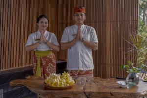 乌布Gdas Bali Health and Wellness Resort的站在桌子前的男人和女人