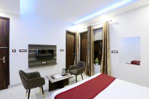 新德里Airport Grand Travel Inn的酒店客房,配有一张床、一张桌子和椅子