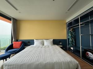 Nam KhêFlamingo Ibiza Hải Tiến的一间卧室配有一张床和一张蓝色椅子