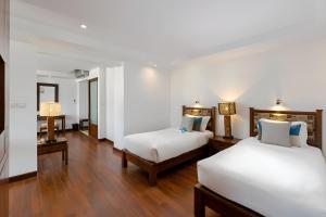 芭东海滩Baan Laimai Beach Resort & Spa - SHA Extra Plus的铺有木地板的客房内的两张床