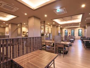 桑名市Hotel Route Inn Kuwana的餐厅设有木桌、椅子和窗户。