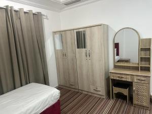 科威特Pyramiza Fahaheel的一间卧室配有一张床、一个梳妆台和镜子
