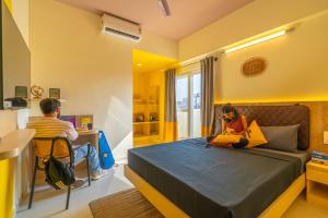 班加罗尔The Hosteller Bangalore, Indiranagar的坐在房间里床边的男孩和女孩