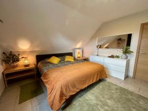 EllezellesAu Coeur des Collines, Gloriette的一间卧室配有一张带黄色枕头和镜子的床