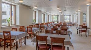 萨翁林纳托特夏季酒店的用餐室设有桌椅和窗户。
