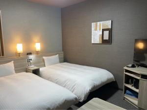 福岛Hotel Route Inn Fukushima Nishi Inter的一间酒店客房,设有两张床和电视