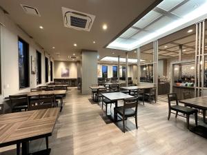 福岛Hotel Route Inn Fukushima Nishi Inter的餐厅设有木桌、椅子和窗户。