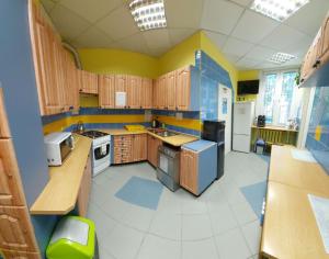 比亚韦斯托克波德拉谢青年旅馆的厨房设有木制橱柜和黄色及蓝色的墙壁