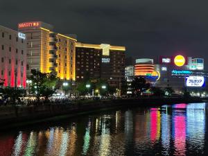 福冈FukuokaKoryou GuestHouse的夜晚的城市,河流和建筑