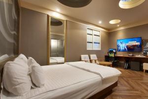 蔚山Palace Hotel的一间卧室配有一张床、一张书桌和一台电视