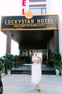 波来古市LuckyStar Hotel的站在酒店前身的身着白色服装的女人