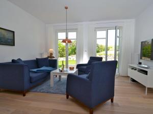 格罗斯齐克Dat Dörphus am Bodden - WG 01的客厅配有2把蓝色椅子和电视