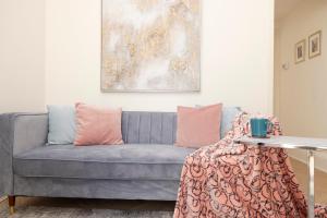 爱丁堡Modern flat in City Centre - For up to 3 guests的客厅配有带粉红色枕头的蓝色沙发
