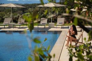 蒙图伊里Es Figueral Nou Hotel Rural & Spa - Adults Only - Over 12的坐在游泳池旁椅子上的女人