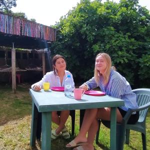 伏罗拉Pinegroove Hostel Vlora的两个女人坐在院子里的野餐桌上